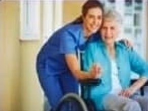 Nurse with a smiling elderly woman seated in a wheelchair