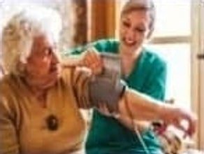 Nurse checking an elderly woman's blood pressure at home